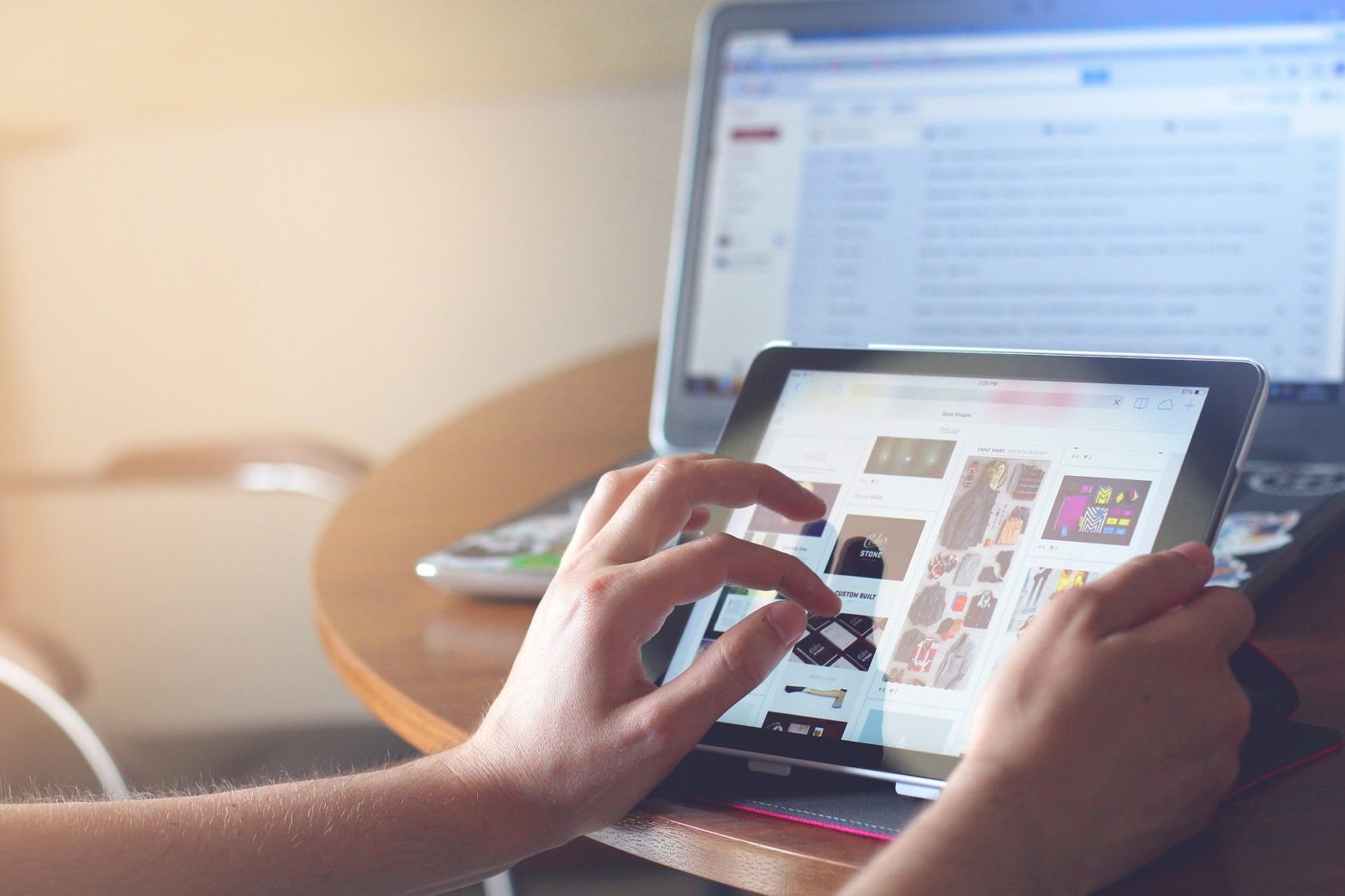 image of person on tablet with laptop in background