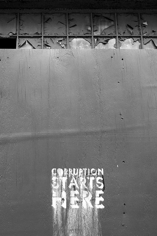 image of grey wall with 'corruption starts here' text