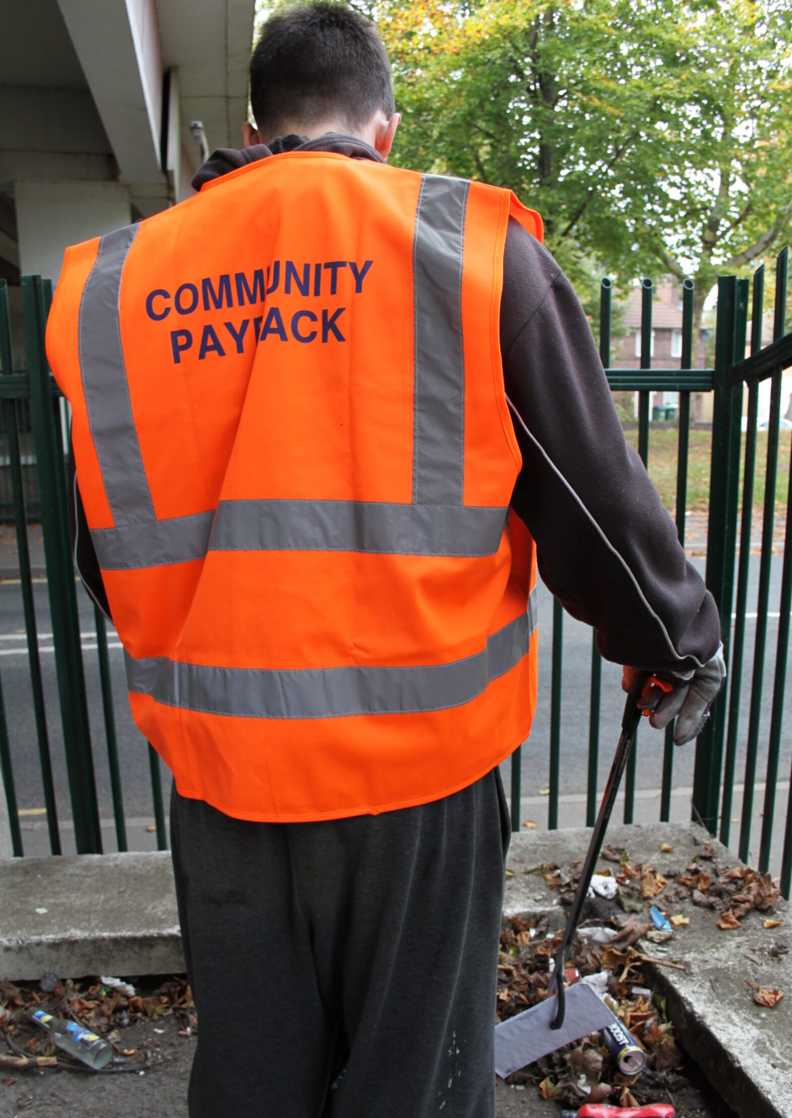 image of a man sweeping up leaves during community service